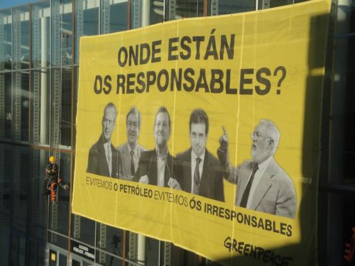Activistas de Greenpeace despliegan una pancarta con fotos de los responsables políticos durante la catástrof