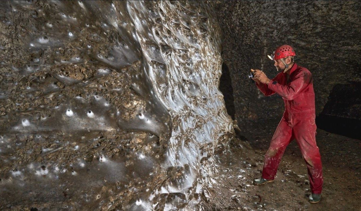 Una telaraña gigante con numerosas arañas en el interior de una cueva oscura