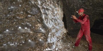 Una telaraña gigante con numerosas arañas en el interior de una cueva oscura