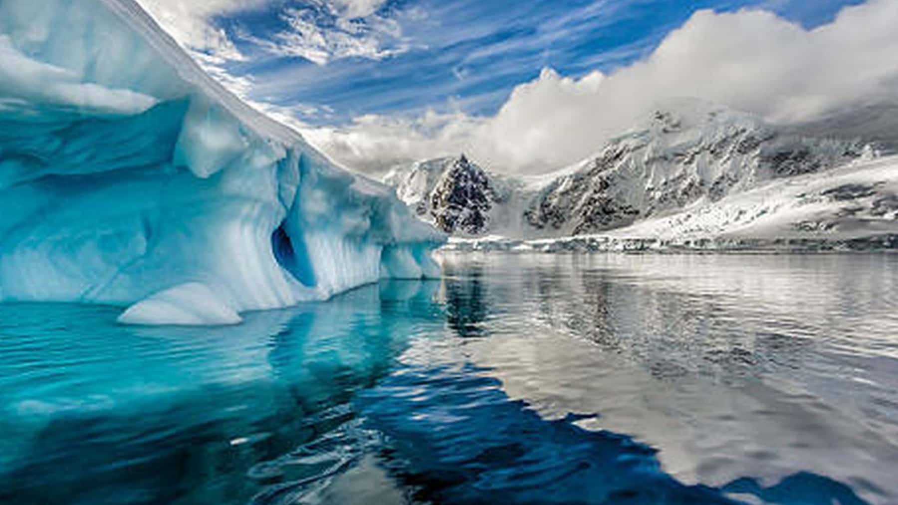 Iceberg flotando en el océano Antártico con montañas nevadas al fondo