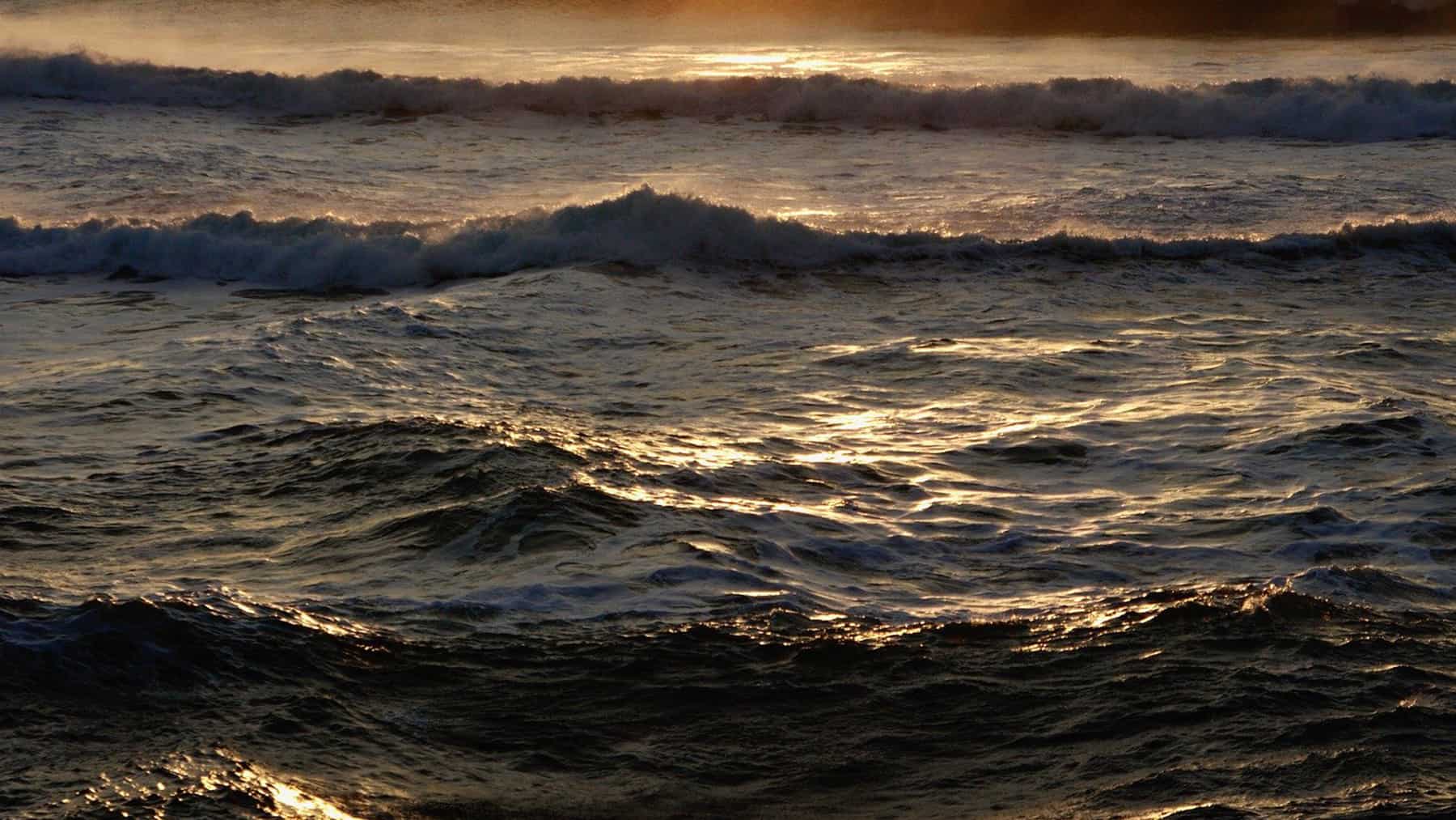 Olas del mar al atardecer con reflejos dorados sobre el agua