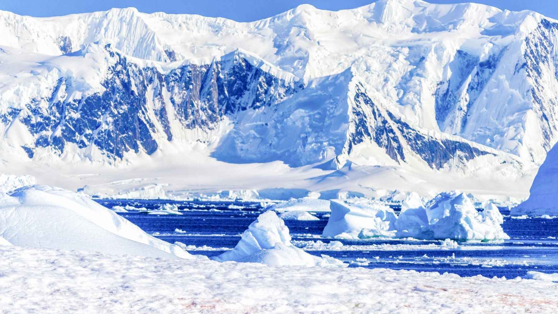 Paisaje costero de la Antártida con icebergs y montañas nevadas, símbolo del deshielo acelerado