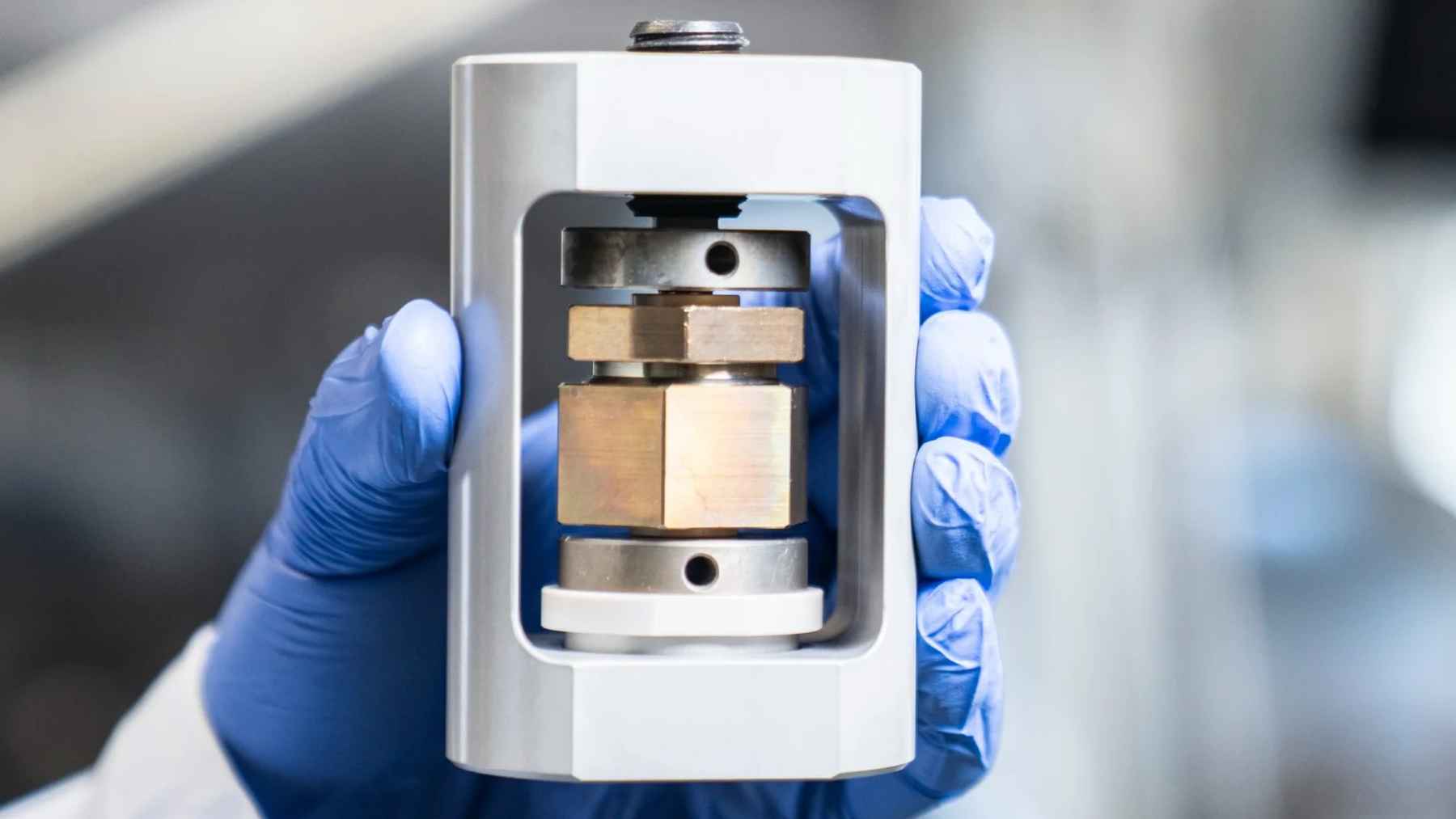 Prototipo de batería de estado sólido sostenido con guantes en un laboratorio