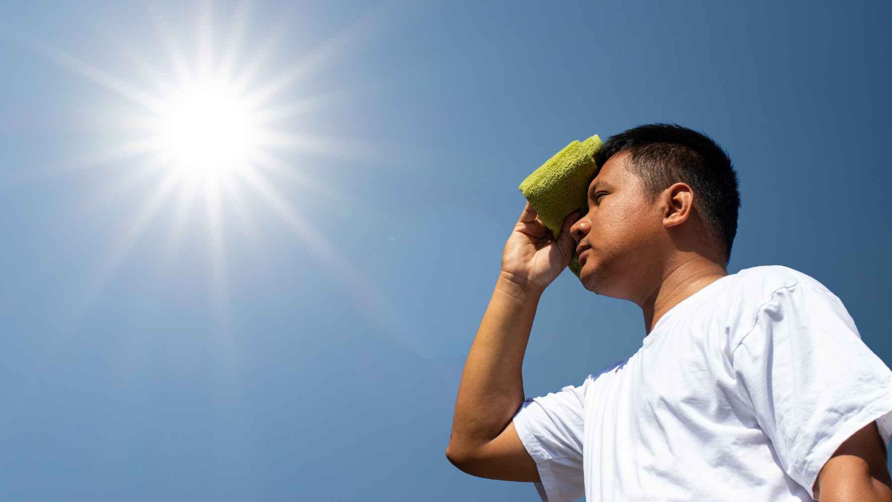 Persona protegiéndose del sol durante una ola de calor con una toalla en la frente