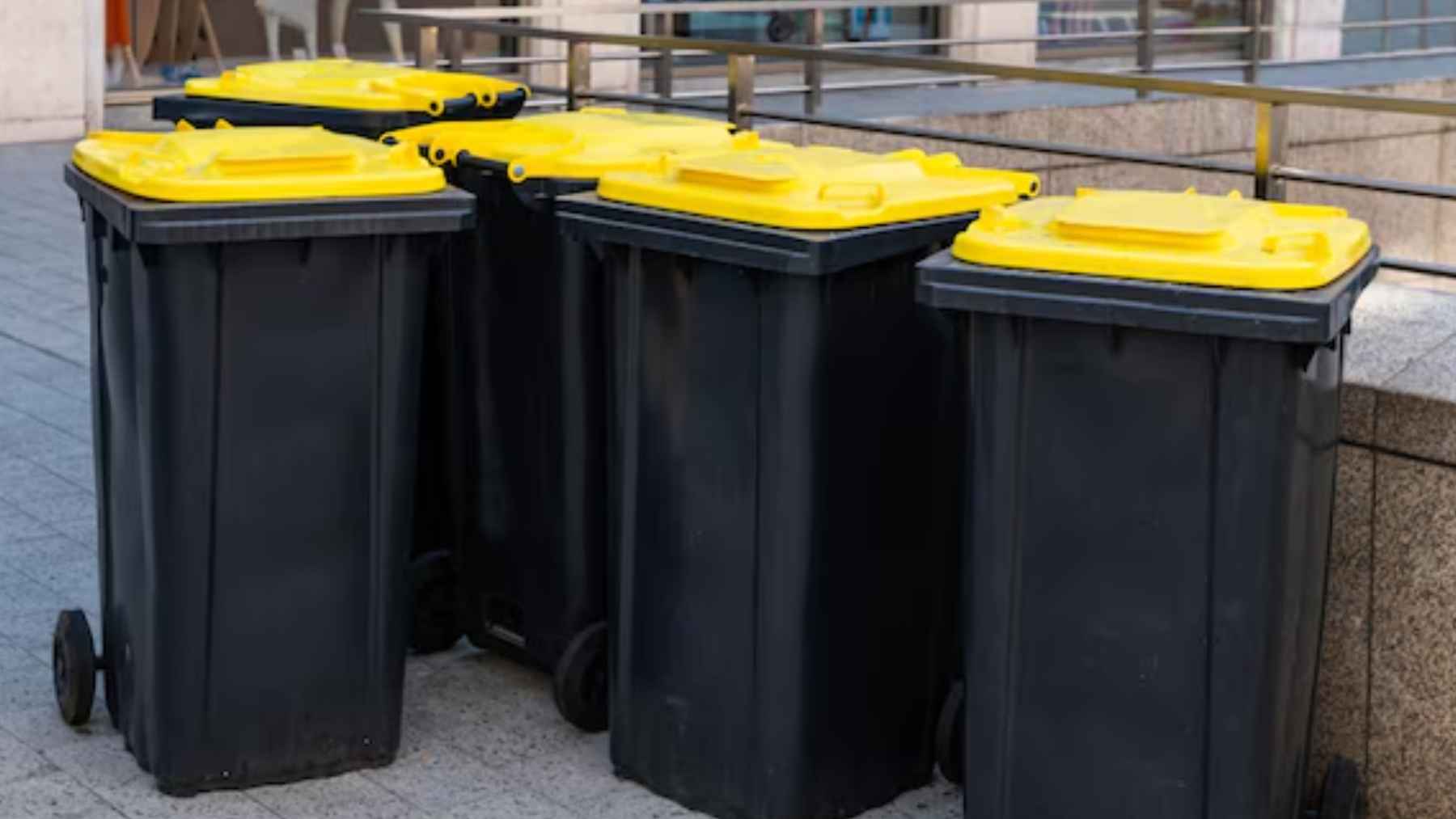 Contenedores amarillos de reciclaje alineados en una calle de Auckland.