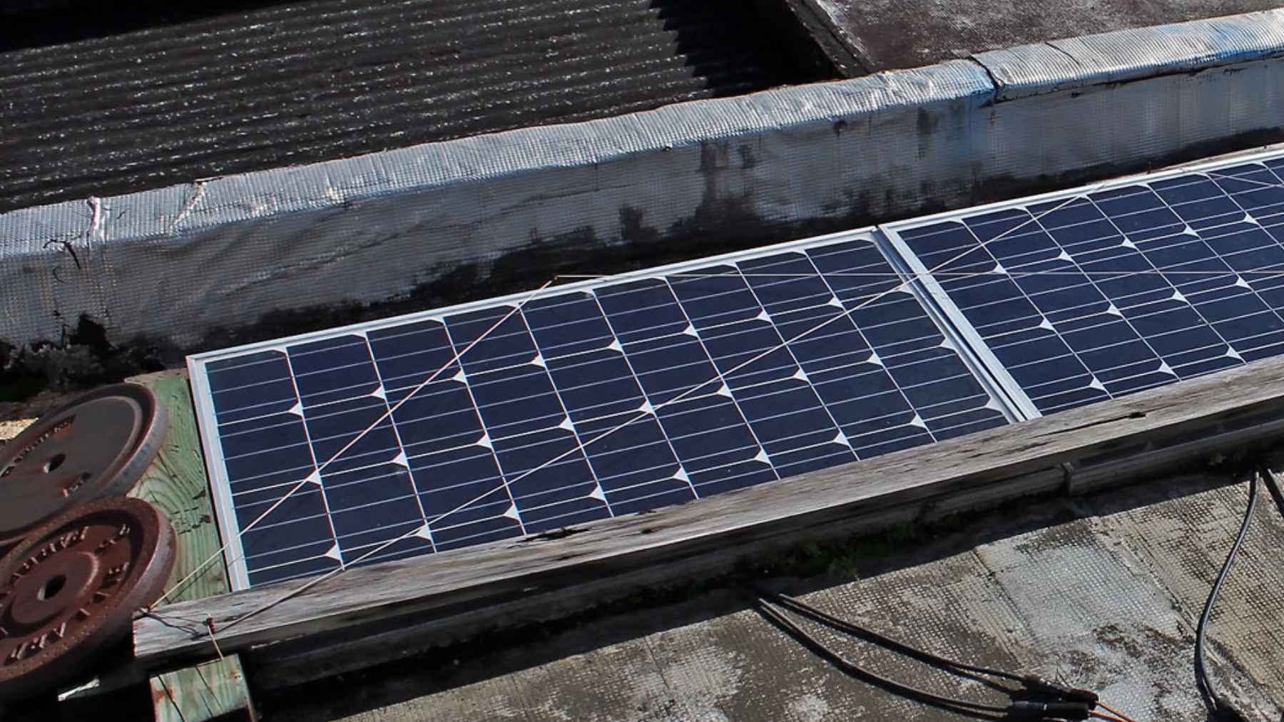 Paneles solares instalados en un tejado, alineados en fila, con cables visibles, tras años de uso.