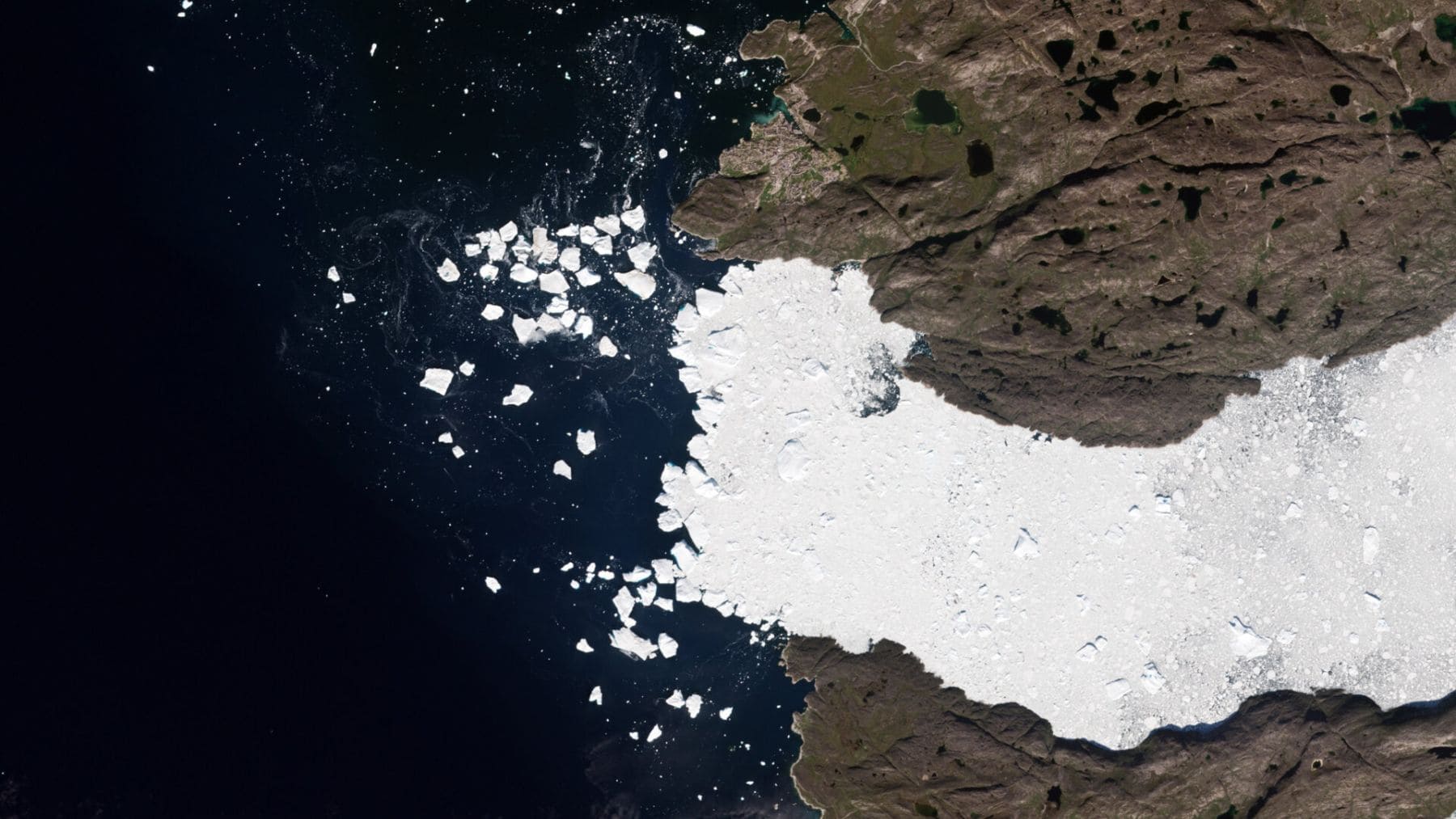 Vista satelital del glaciar Sermeq Kujalleq en Groenlandia liberando hielo al océano en la Bahía de Disko