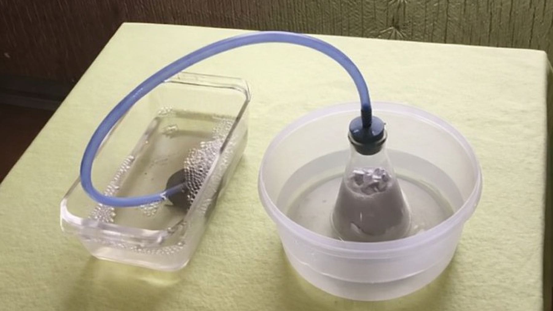 Experimento de producción de hidrógeno a partir de agua mediante reacción química en laboratorio con sistema de tubos y burbujas.