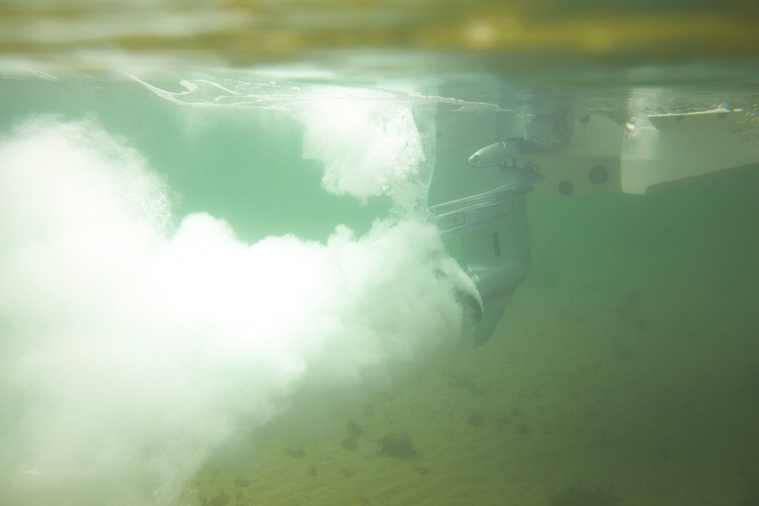 Hélice de barco bajo el agua con cavitación generando burbujas y ruido submarino.