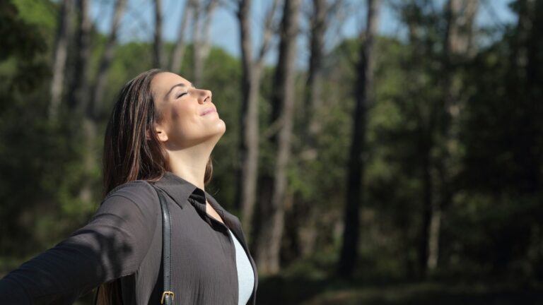 Mujer respirando aire limpio en la naturaleza frente a la contaminación global según el informe IQAir 2025.