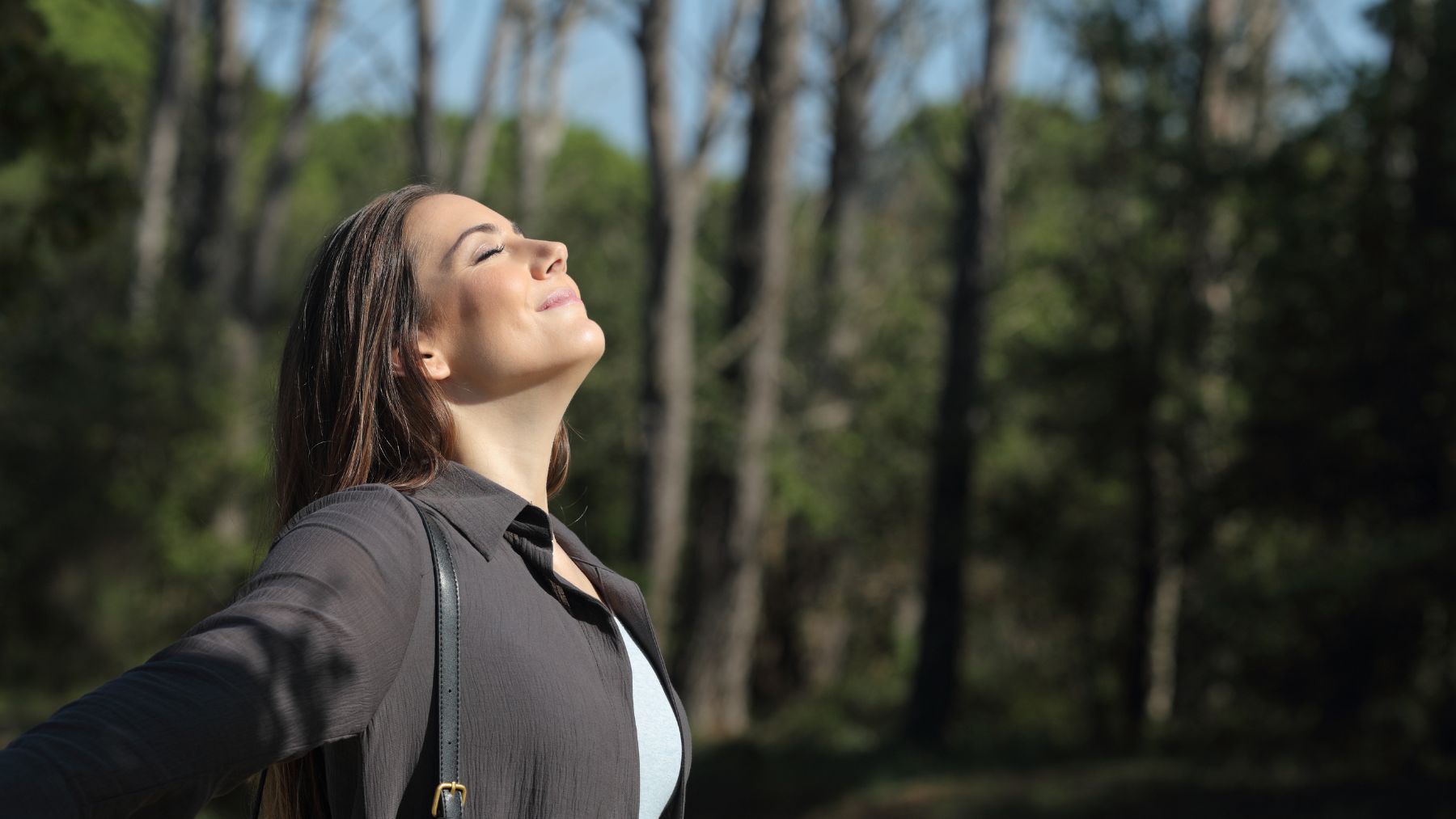 Mujer respirando aire limpio en la naturaleza frente a la contaminación global según el informe IQAir 2025.