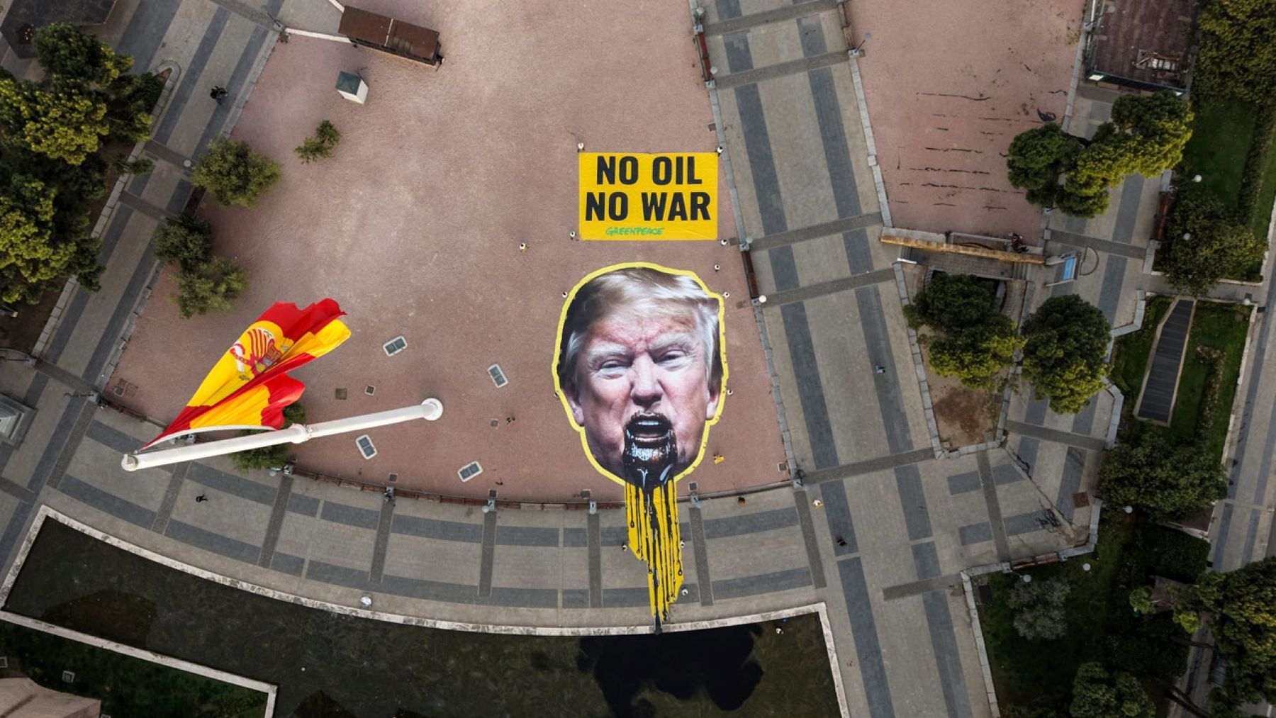 Abandono de los combustibles fósiles a nivel global con pancarta de Trump vomitando petróleo en protesta ambiental