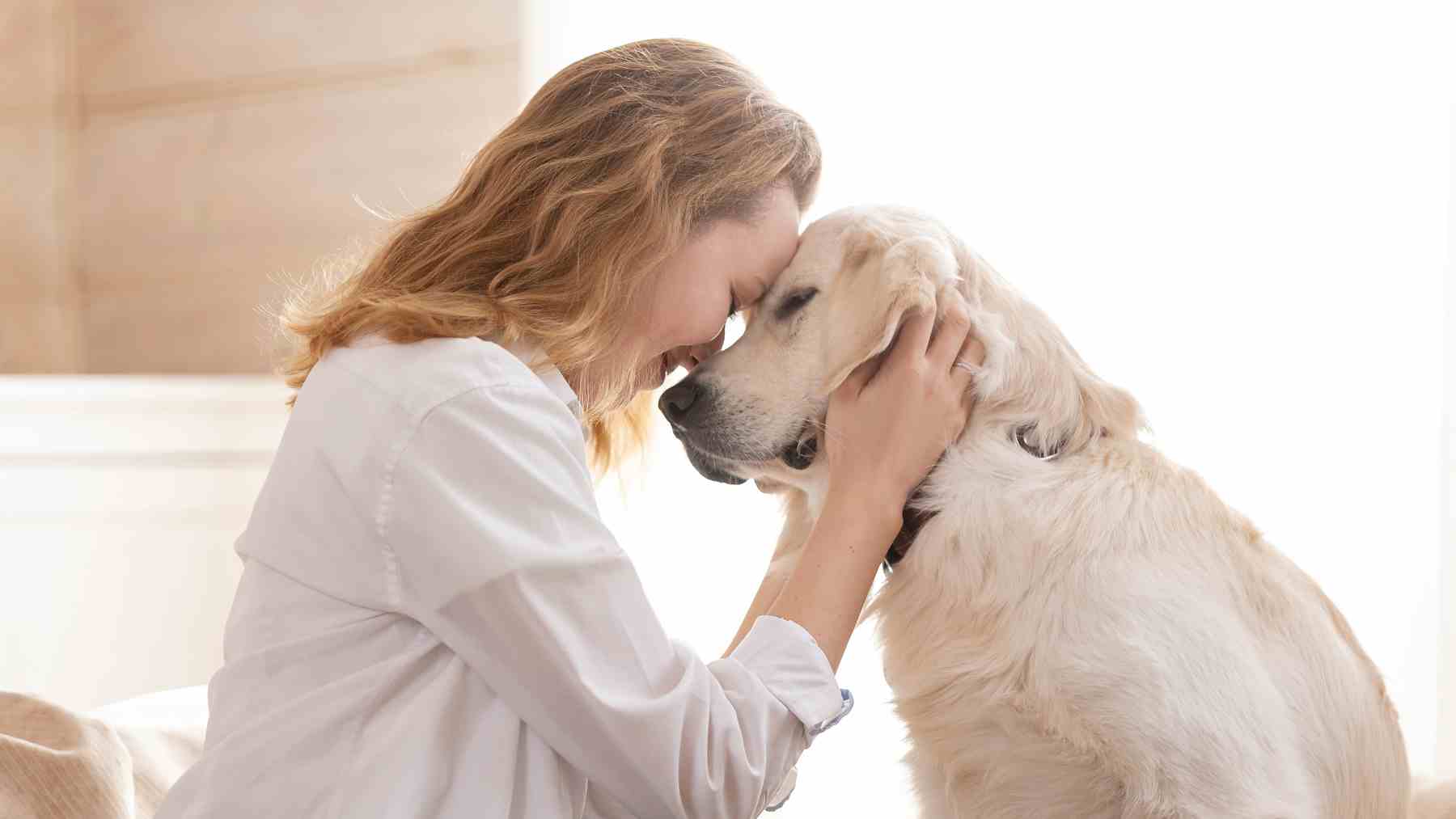 Mujer despidiéndose de su perro con gesto cariñoso antes de salir de casa, reflejando vínculo emocional.