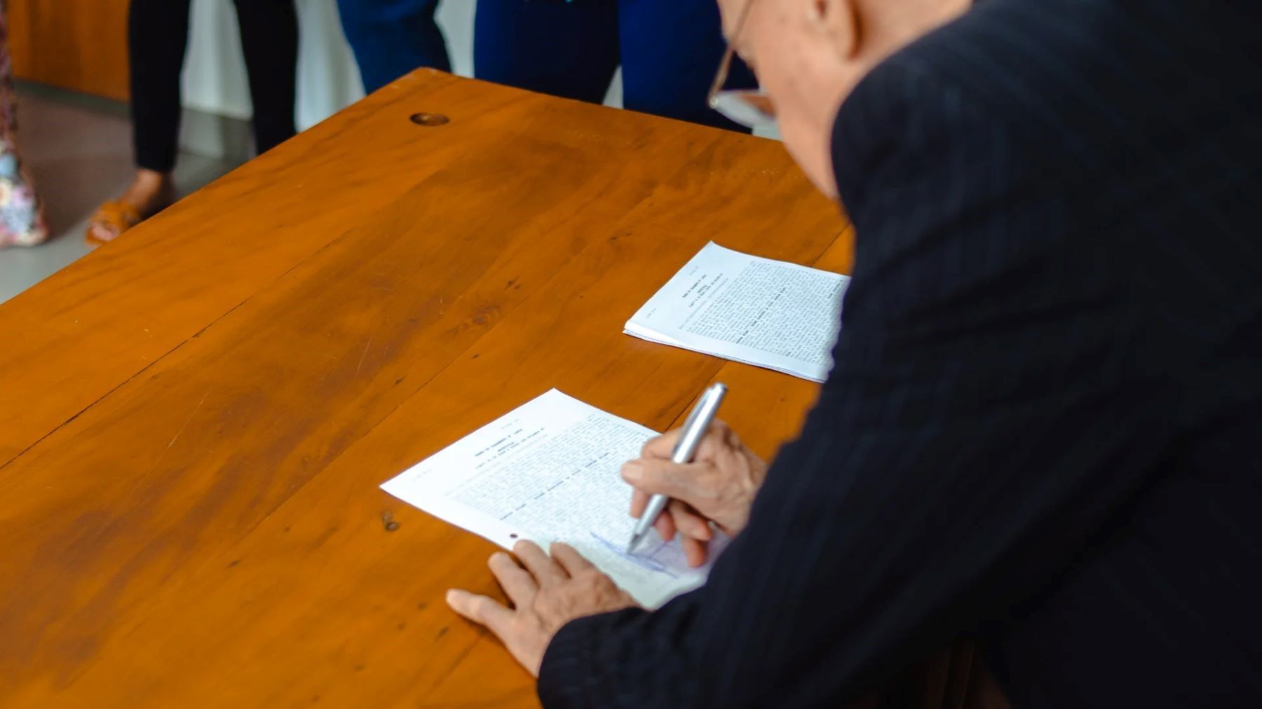 Persona firmando el testamento solidario para proteger la naturaleza junto a iniciativas de conservación ambiental