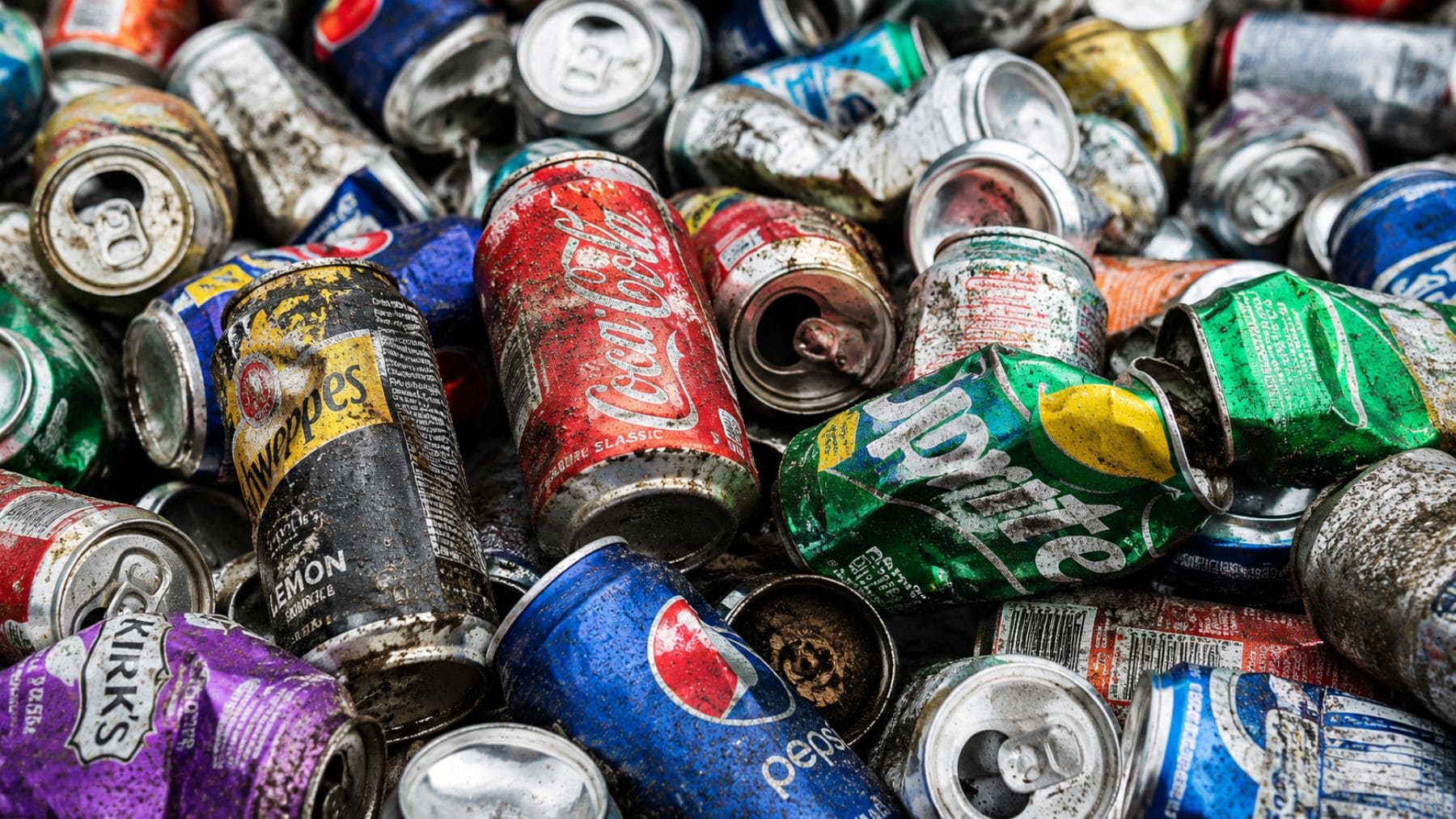 Montaña de latas usadas y botellas recicladas acumuladas para reciclaje tras años de recogida de residuos.