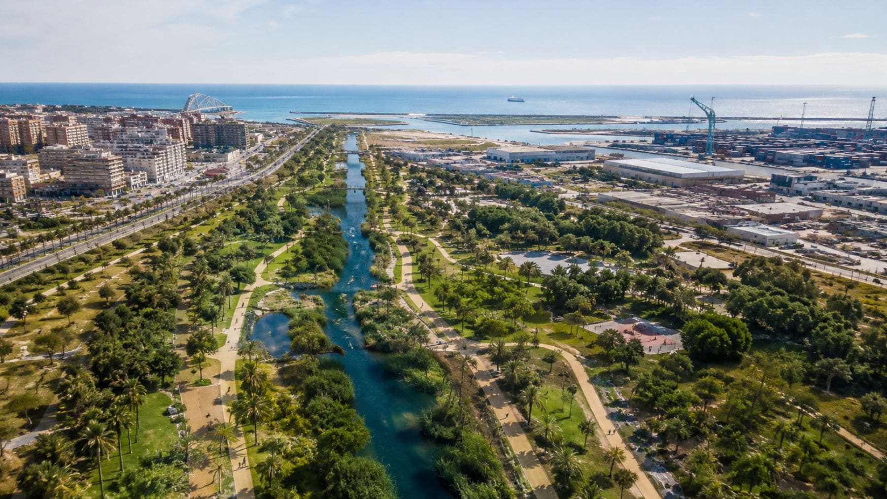Vista aérea del futuro Parque de Desembocadura de Valencia con zonas verdes, agua y conexión al mar.