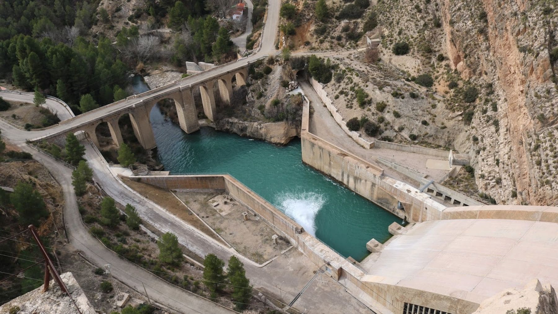 Vista aérea de una presa hidroeléctrica española con sistemas de desagüe y canalizaciones de agua.