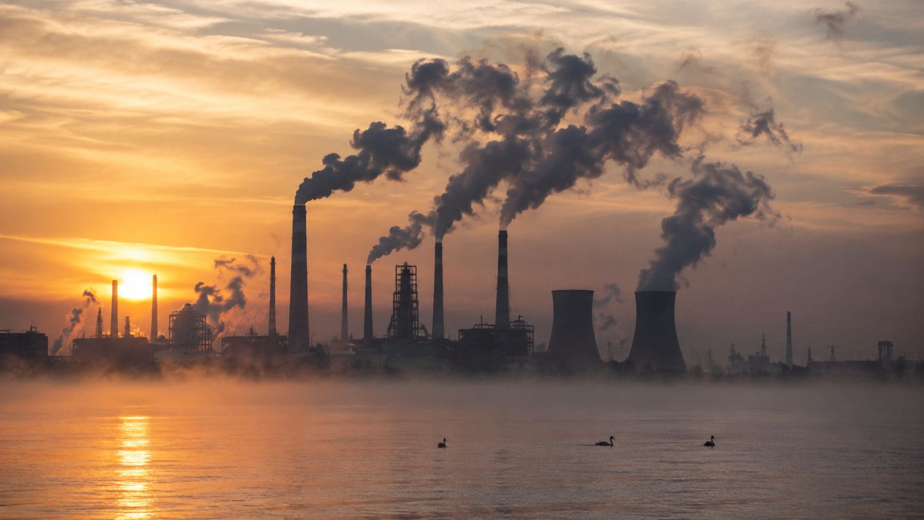 Fábricas industriales expulsando gases contaminantes relacionados con químicos eternos y contaminación atmosférica.