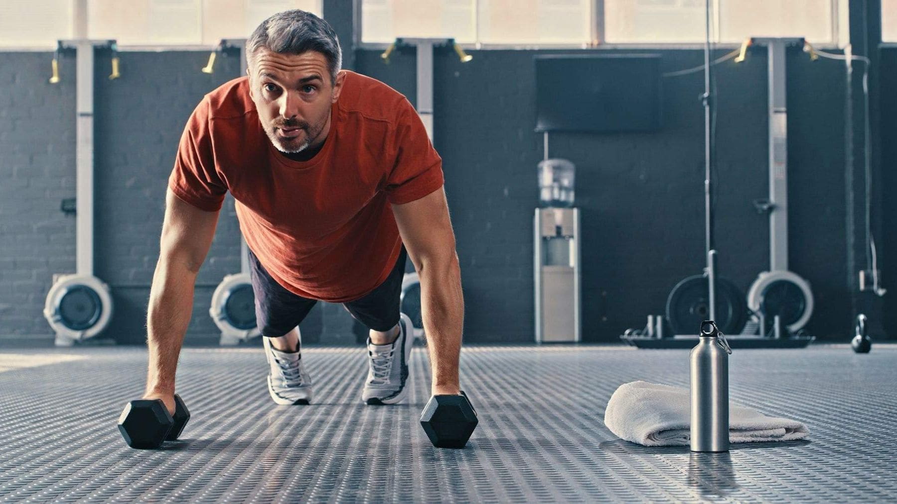 Hombre de más de 40 años entrenando fuerza en un gimnasio para ganar masa muscular y cuidar la testosterona.