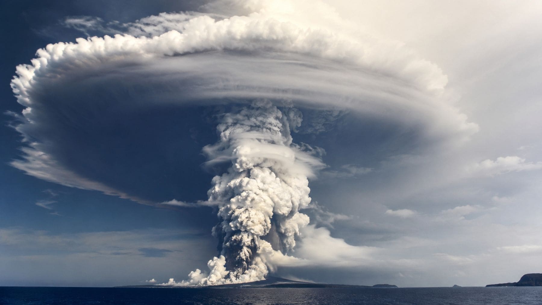 Erupción del volcán submarino Hunga Tonga-Hunga Ha’apai generando una enorme nube atmosférica sobre el océano Pacífico.