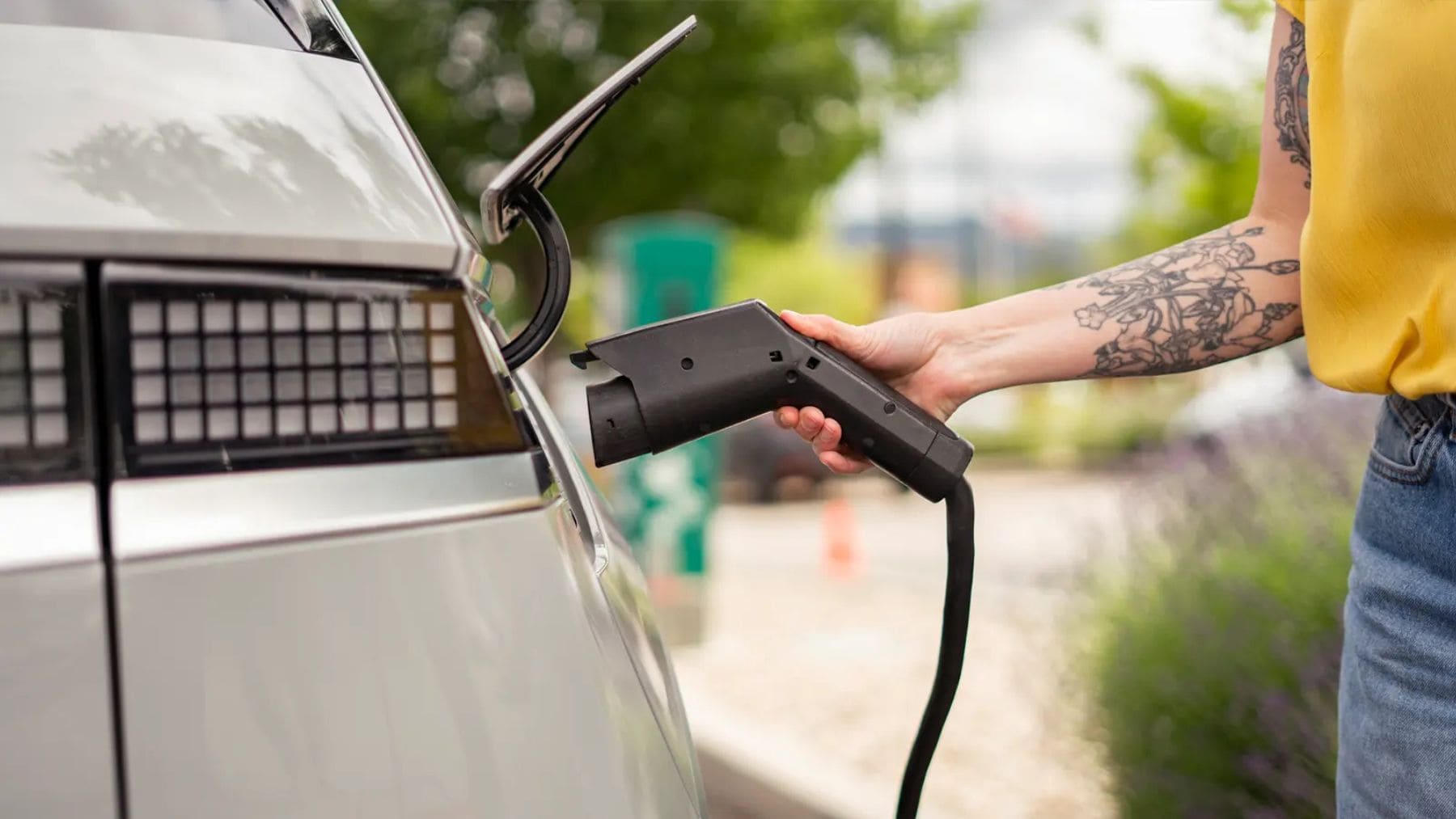 Persona cargando un coche eléctrico en un punto de recarga, reflejo del crecimiento de las ventas de vehículos eléctricos de segunda mano en España.