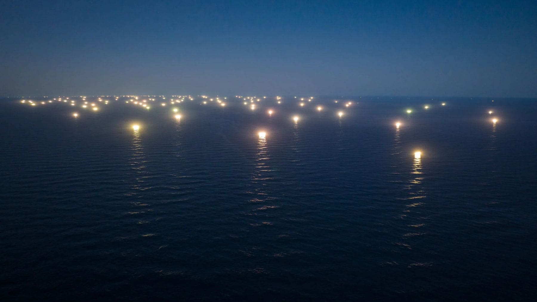 Flota pesquera china iluminando el océano durante operaciones de pesca industrial nocturna
