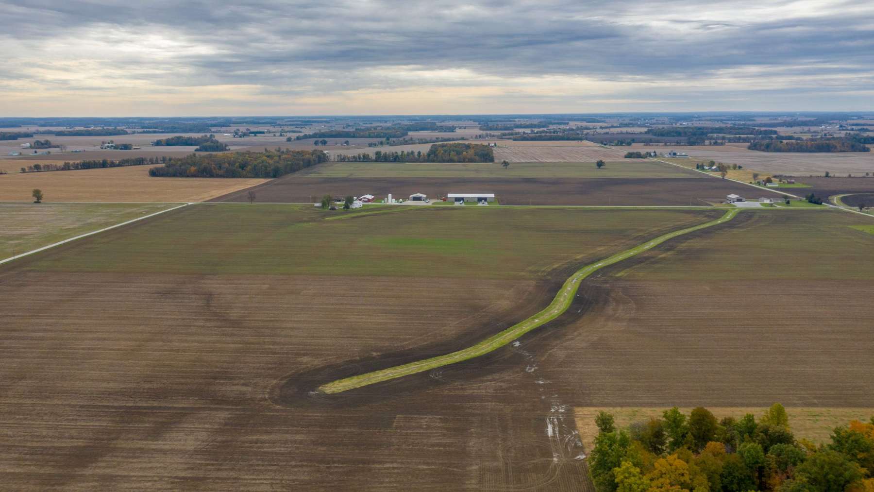 Vista aérea de campos de cultivo de Ohio atravesados por un cauce cubierto de hierba