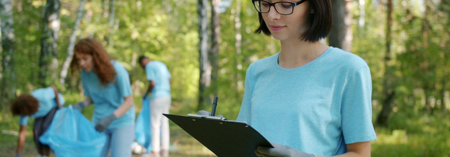 Técnica con carpeta tomando notas en un bosque