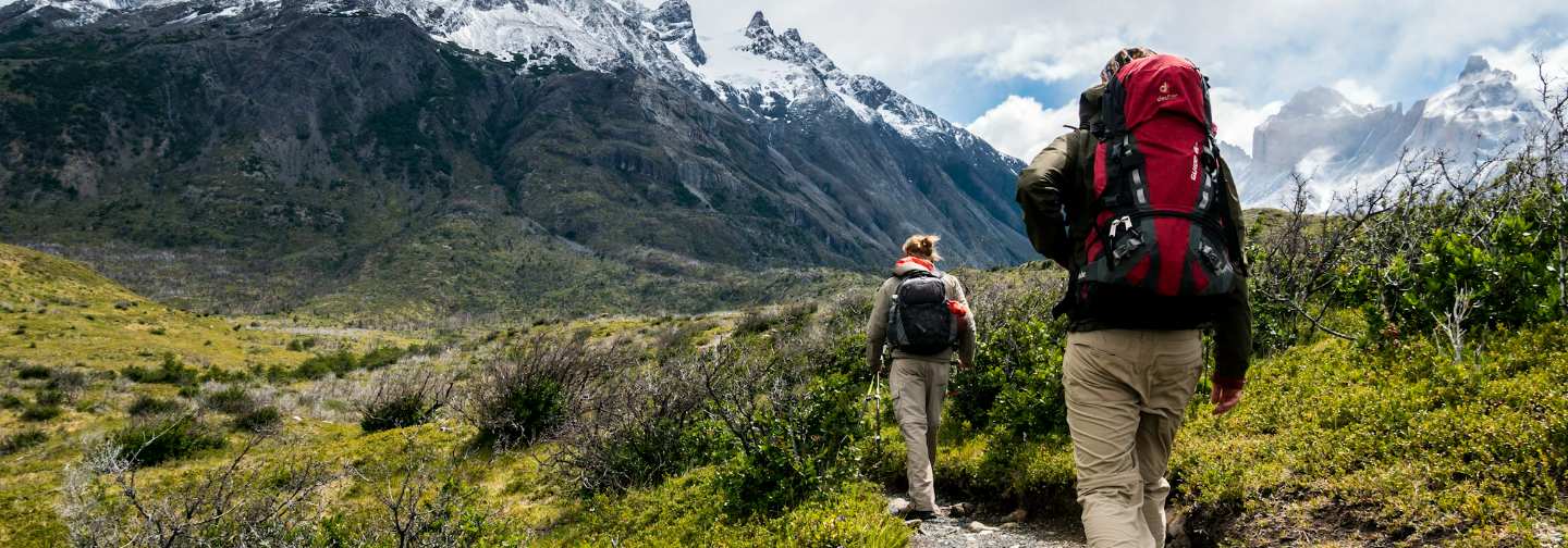 Senderistas caminando hacia montañas nevadas