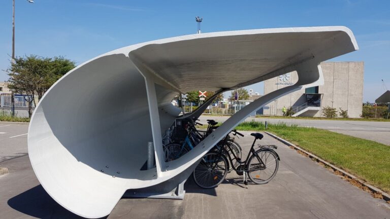 Marquesina curva hecha con un tramo de pala de aerogenerador que cubre bicicletas aparcadas en Aalborg