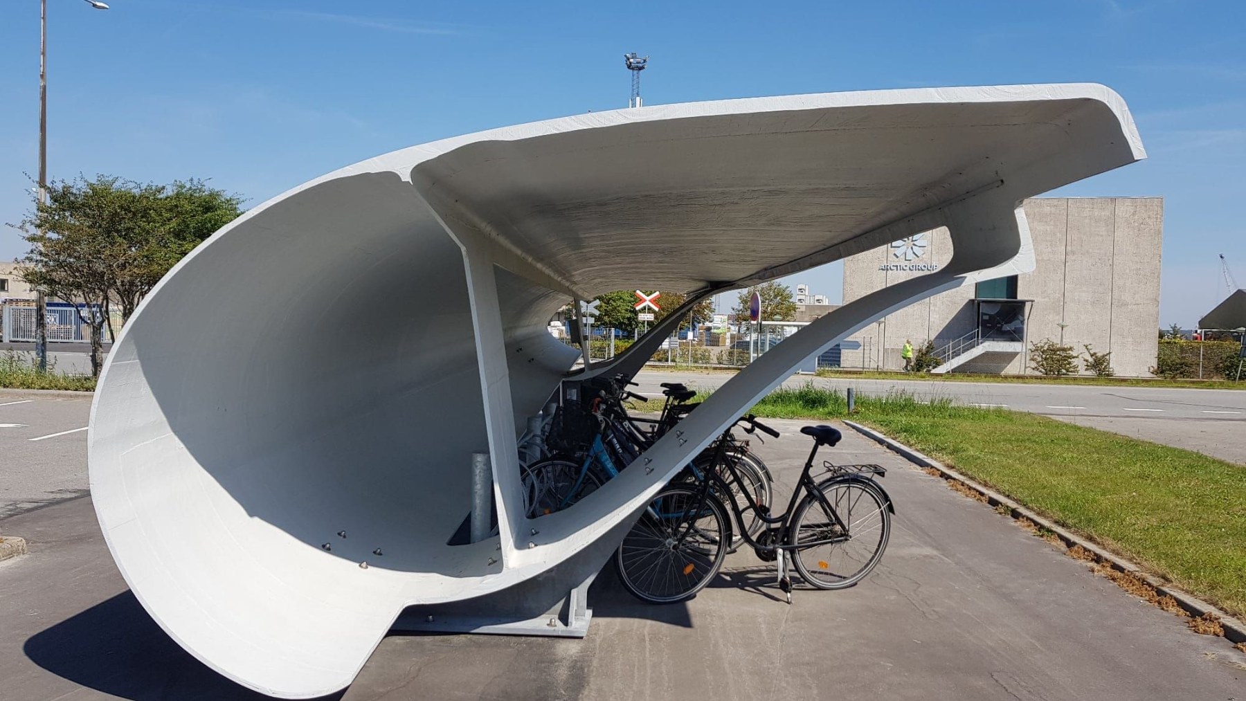 Marquesina curva hecha con un tramo de pala de aerogenerador que cubre bicicletas aparcadas en Aalborg