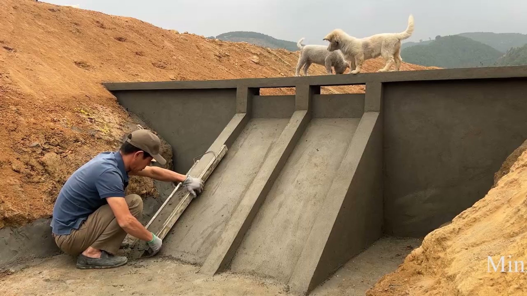 Hombre construyendo con cemento el canal de una pequeña central hidroeléctrica