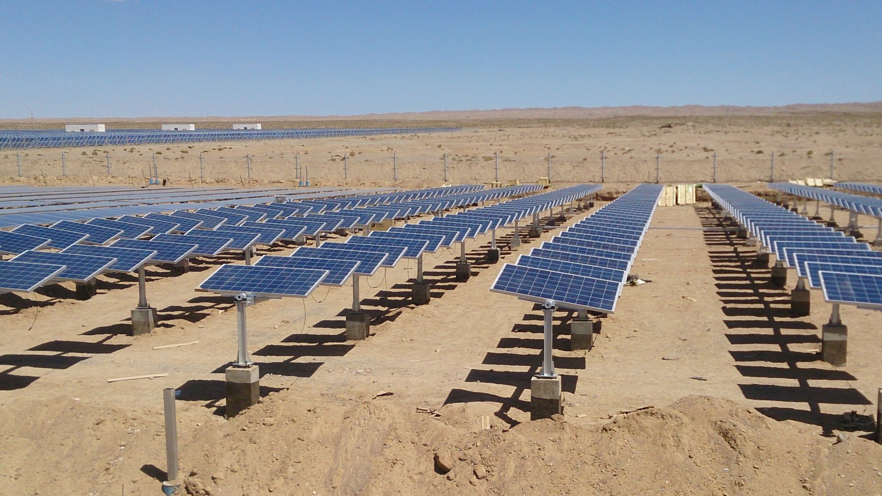 Filas de paneles solares montados sobre seguidores de un eje en un terreno árido