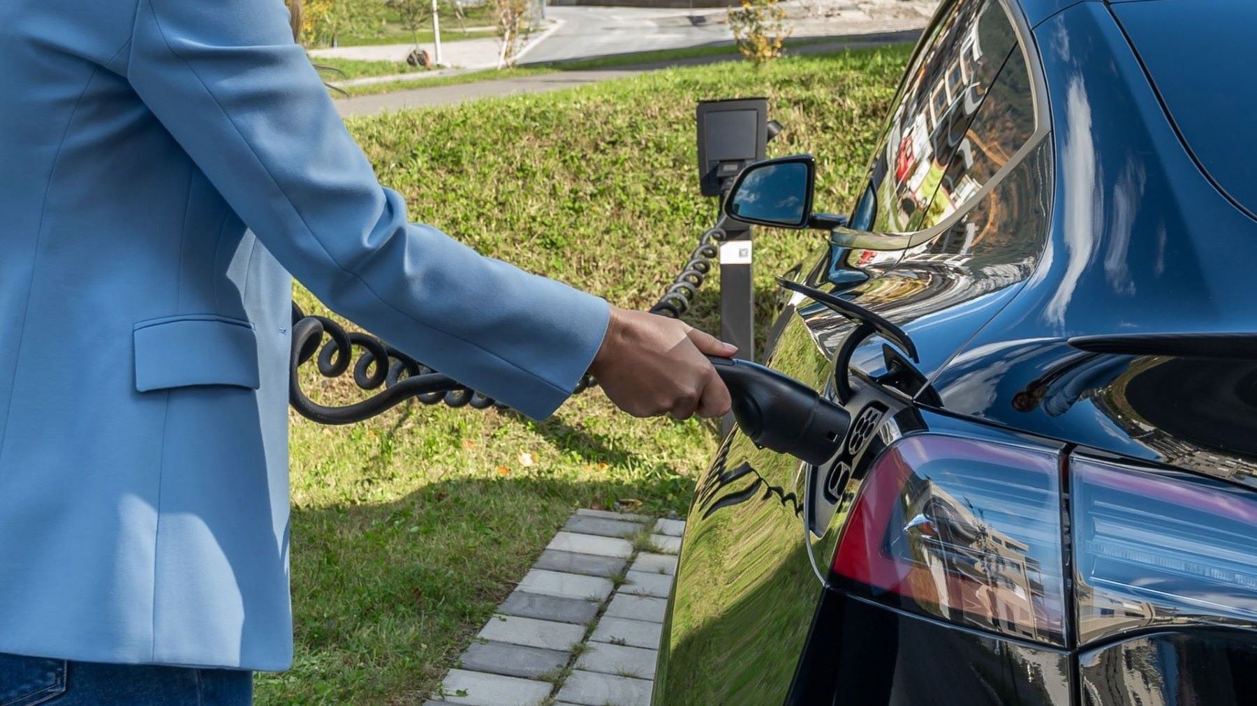 Vehículo eléctrico conectado a una estación de recarga ultrarrápida en un área de servicio.
