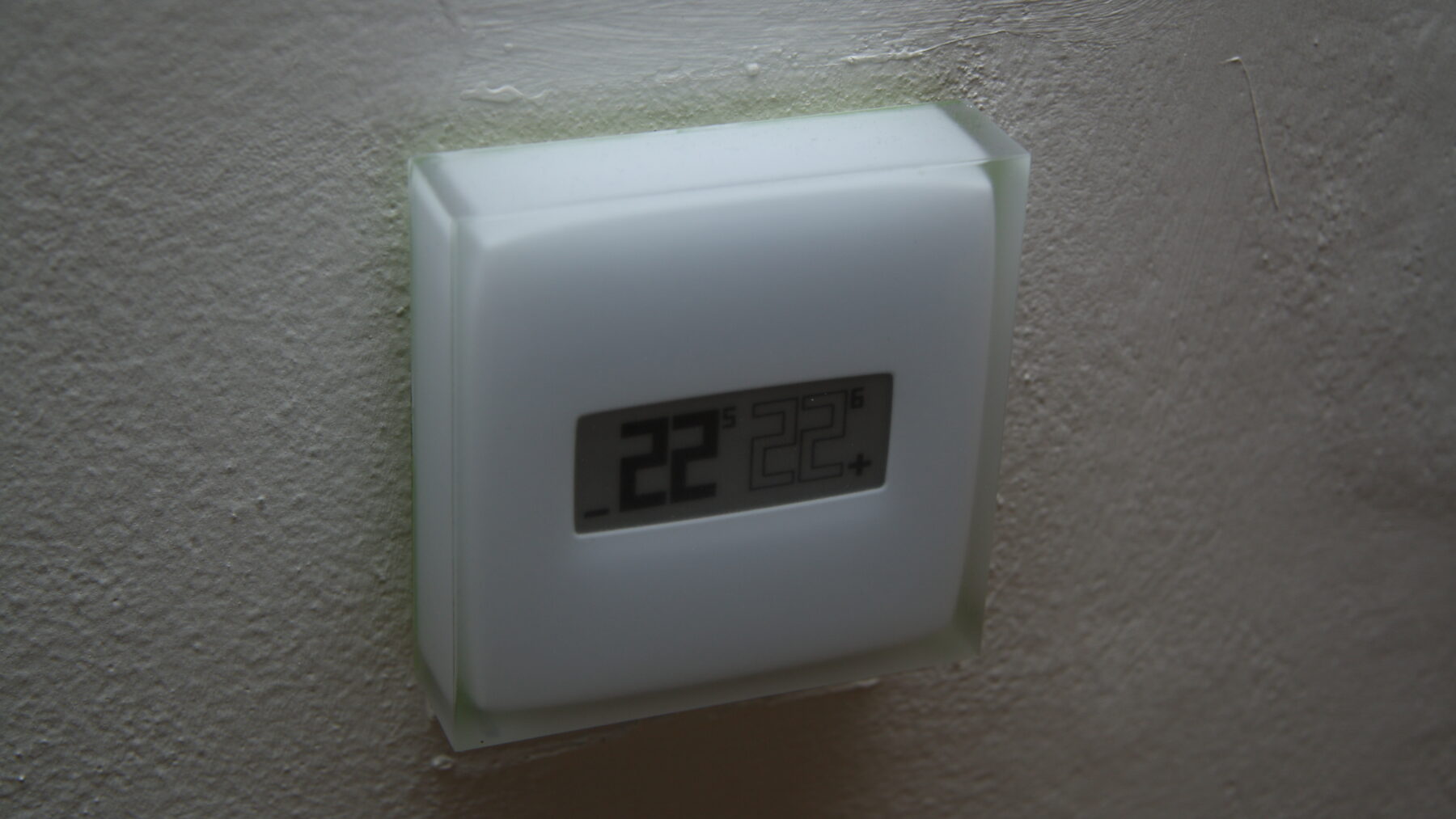 Termostato digital de pared en una vivienda con la pantalla marcando 22 grados centígrados