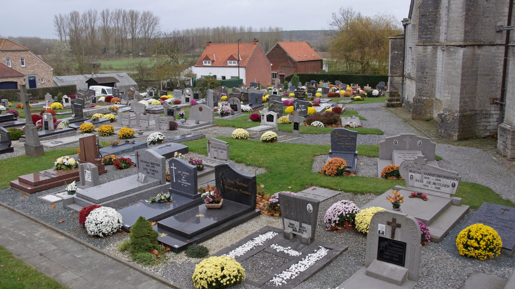 Tumbas de un cementerio decoradas con macetas de crisantemos en flor durante Todos los Santos