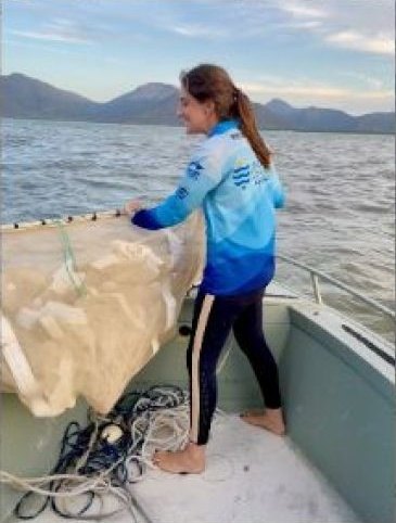 Investigadora recogiendo una red de arrastre en una barca durante un muestreo de praderas marinas