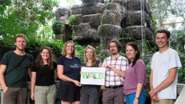 Investigadores del experimento de sequía B2-WALD en la selva tropical de Biosfera 2, con un cartel del proyecto