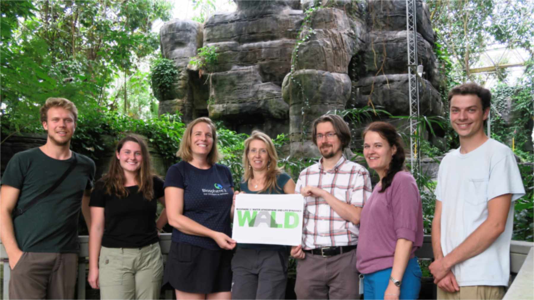 Investigadores del experimento de sequía B2-WALD en la selva tropical de Biosfera 2, con un cartel del proyecto