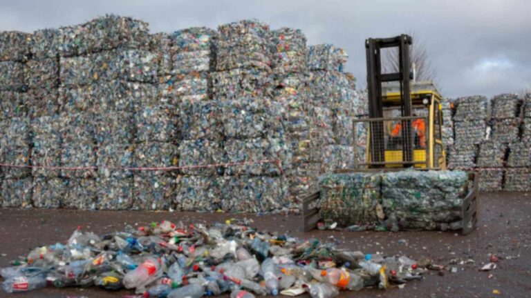 Balas de envases de plástico prensados y una carretilla elevadora en una planta de reciclaje de botellas