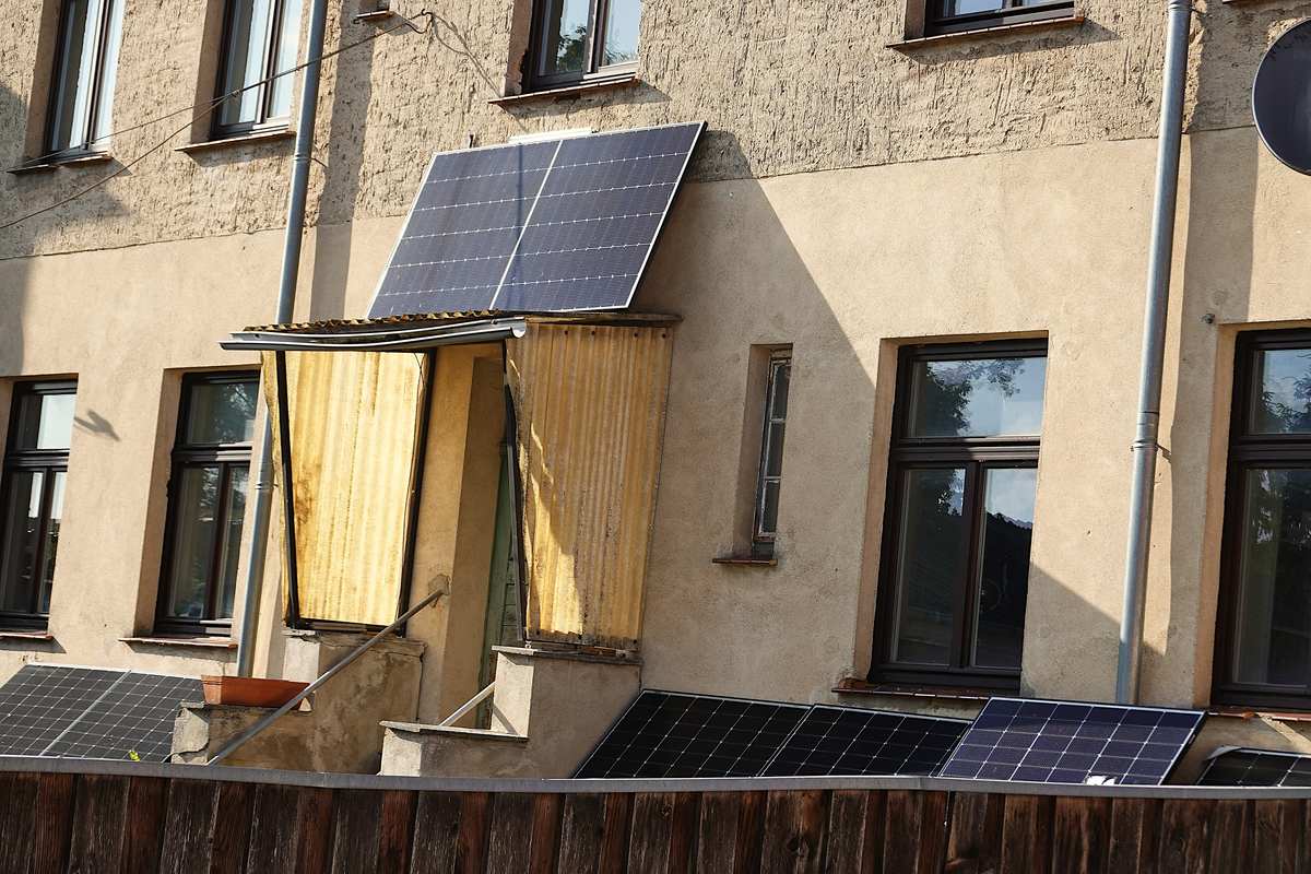 Placas solares enchufables sobre el tejadillo de una entrada y apoyadas junto a la fachada de un edificio de viviendas en Wesenberg, Alemania