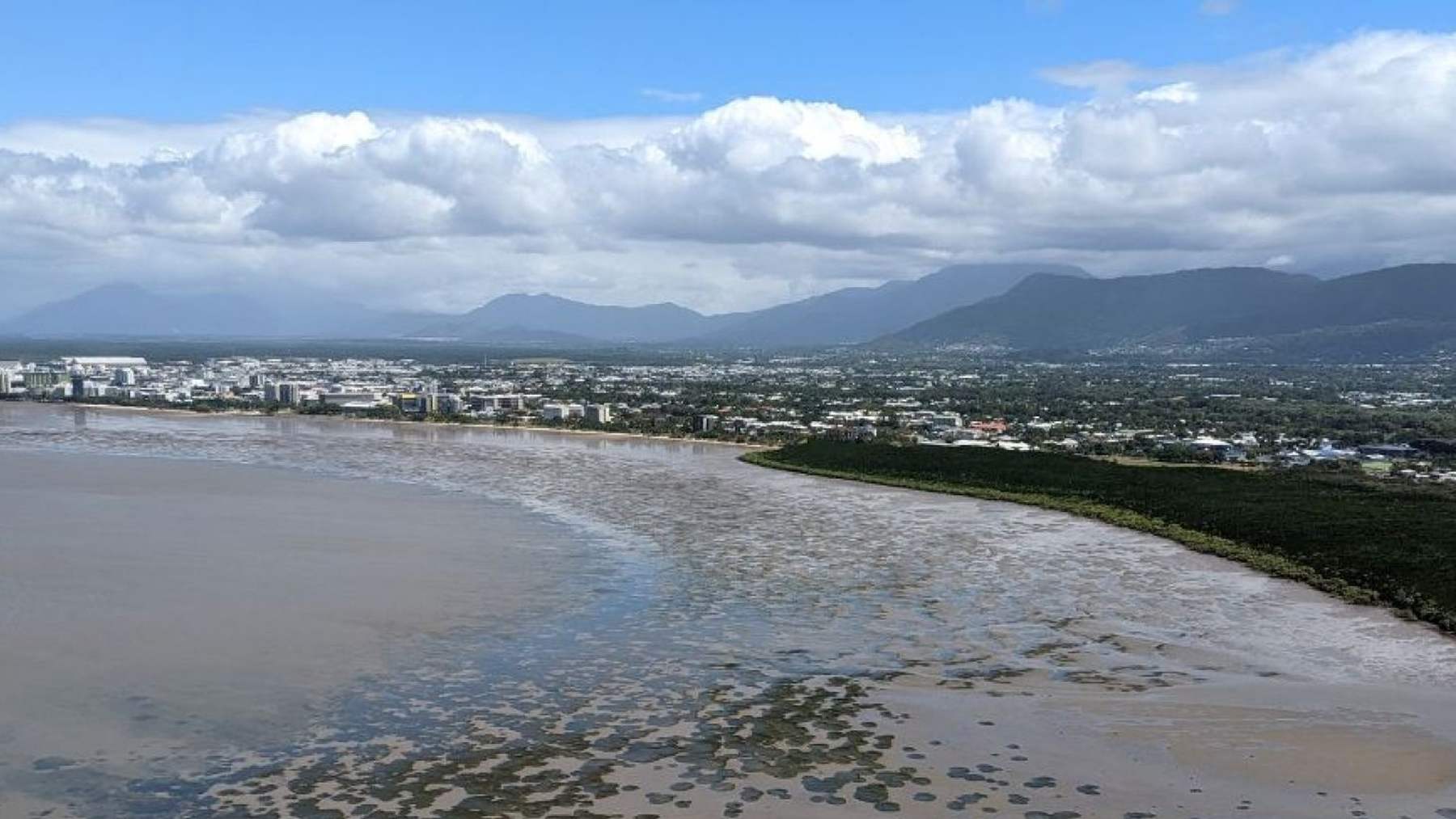 Vista aérea de las praderas marinas de la bahía de Cairns con la marea baja, el manglar y la ciudad al fondo