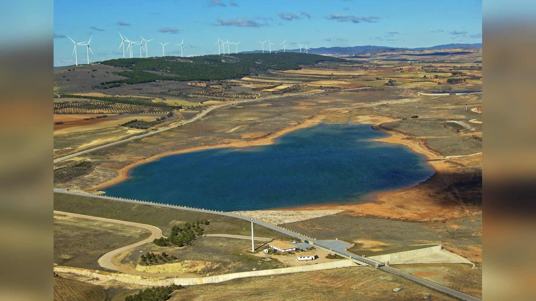 Vista aérea del embalse de Campos del Paraíso, que regula el agua de la Llanura Manchega, con la presa y sus edificios en primer plano