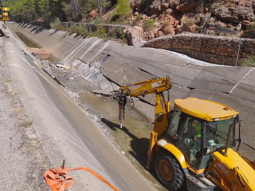 Una retroexcavadora con martillo rompe el hormigón dañado del canal vacío del Acueducto Tajo-Segura